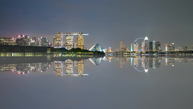 4k time lapse of sunset day to night scene at Marina Bay Singapore city skyline with reflection effect. Tilt up