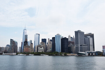 Fototapeta na wymiar Skyscrapers of manhattan located near rippling water of new york bay against cloudy blue sky