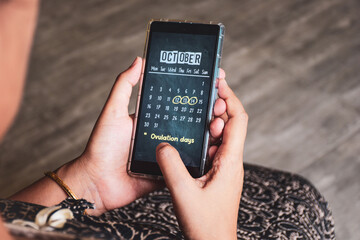 Woman marking her probable ovulation days on digital calendar application. Selective focus, fertile...