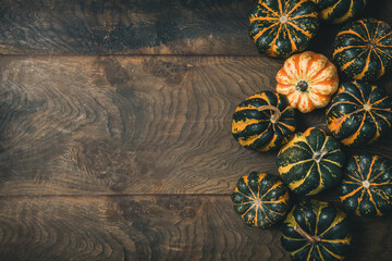 Various small pumpkins with a striped pattern on wooden background