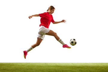 Obraz na płótnie Canvas Athletic young woman, football player in motion during game, hitting ball on grass field isolated on white background. Concept of sport, competition, action, success, motivation. Copy space for ad