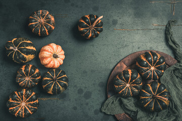 Various small pumpkins with a striped pattern on dark green background
