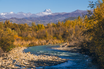 Beautiful autumn landscape mountain river, yellowed trees, mountains with snowy peaks. Charming...