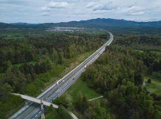 Highway road in rural Slovenia surrounded with green forest trees, photographed with a drone camera from above