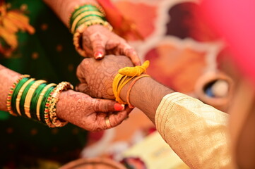 Indian groom Tie a Turmeric Thread on hand of bride. Hands of bride and Groom in hindu wedding. Marathi Wedding Ceremony. Maharashtra Culture. Hindu wedding rituals and ceremony. Yellow knot