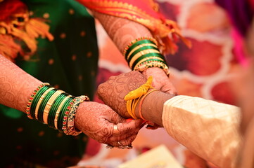 Indian groom Tie a Turmeric Thread on bride hand. Hands of bride and Groom in hindu wedding. Marathi Wedding Ceremony. Maharashtra Culture. Hindu wedding rituals and ceremony. Yellow knot