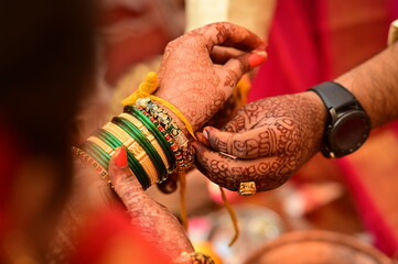 Indian bride Tie a Turmeric Thread on hand of groom.  Yellow knot. Hands of bride and Groom in hindu wedding. Marathi Wedding Ceremony. Maharashtra Culture. Hindu wedding rituals and ceremony. 