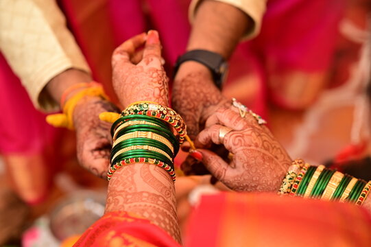 Indian bride Tie a Turmeric Thread on hand of groom. Close Up Hands of bride and Groom in hindu wedding. Marathi Wedding Ceremony. Maharashtra Culture. Hindu wedding rituals and ceremony. Yellow knot
