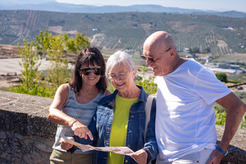Smiling group of mature seniors visiting a historic castle in Andalusia, Spain, looking at the map...