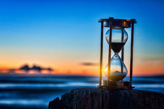 Hourglass or sand timer in front of a beatiful clear sunrise or sunset.