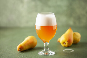 Boozy Refresing Cold Hard Pear Cider or Craft Fruit Beer in a Pint Glass on wooden table. Copy space