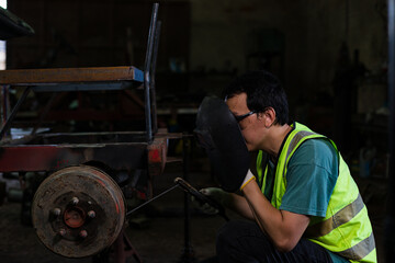 Auto mechanic repairs an old car, young man use hand tools to repair old steel agricultural vehicles.