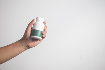The man's hand held a medicine bottle containing antibiotics against a white background.