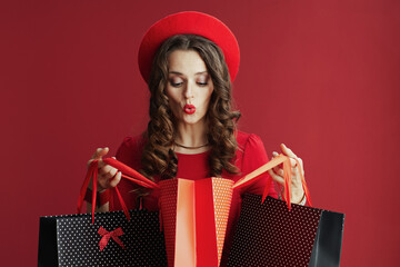 surprised stylish woman in dress and beret with shopping bags