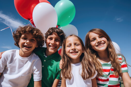Happy cheerful children with bunch of colorful balloons in colors of Italian flag over the blue sky