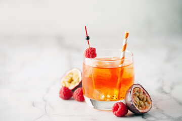 Fresh sparkling berry drink with passion fruits and raspberries in wine glass.
