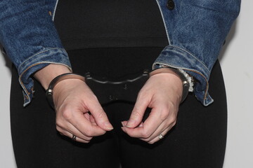 Fototapeta premium A closeup of the handcuffs on woman who has been arrested for a crime. The prisoner is awaiting transport to jail.
