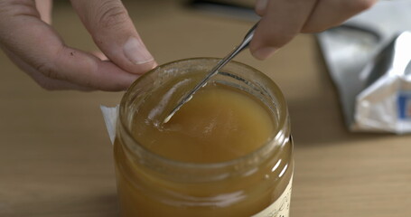 Grabbing honey from pot with knife close-up i