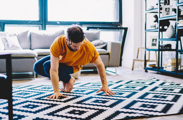 Young man dressed in active wear doing yoga exercises during morning training at home interior