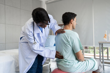 Obraz premium African American Doctor or Physiotherapist working examining treating of caucasian patient, back stretching and exercise, in clinic 