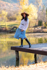 Autumn lake woman. She stands by a pond on a wooden pier in autumn and admires nature. The concept of tourism, weekends outside the city.
