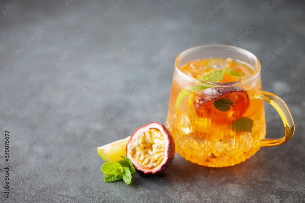 Wall mural fruit ice tea. refreshing summer drink with syrup, passion fruit, lime, mint and ice. glass with col