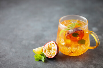 Fruit ice tea. Refreshing summer drink with syrup, passion fruit, lime, mint and ice. Glass with...