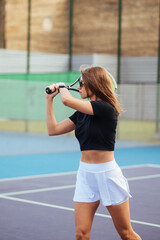 Attractive sporty woman is actively playing tennis on the court with a racket in her hands. Hobby tennis.