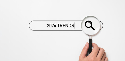 Hand holding magnifier glass with 2024  trends  searching bar for optimization 2024 business marketing trends and planing change concept.