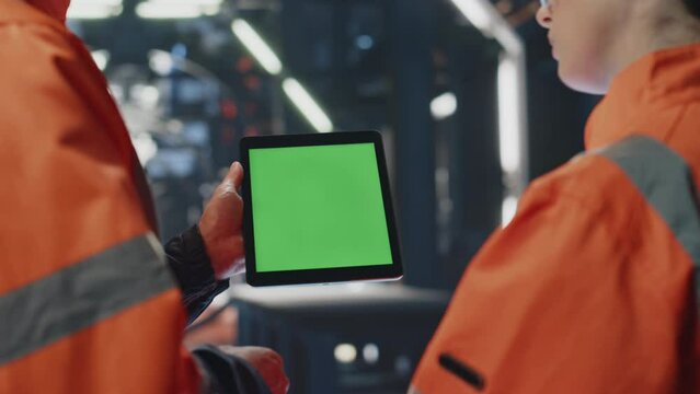 Factory colleagues watching green screen tablet in industry facility close up.