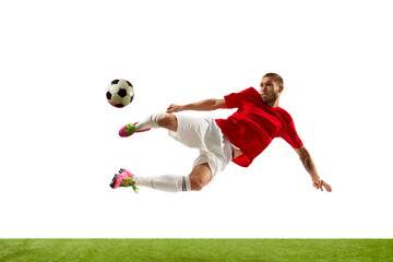 Portrait of young Caucasian soccer football player looks confident practicing kicking ball in motion against white background on green grass.