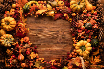 Autumn composition on a rustic wooden background. Decorative pumpkins, various leaves, pine cones, nuts. Orange, yellow, red  and brown aesthetics. 