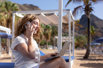 Relaxing carefree woman sitting on beach, woman surfing the internet, thinking and planning new work project