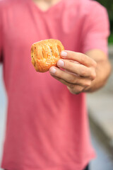 Vertical frame of hands holding pastries, fast food snack concept. Background with selective focus and copy space