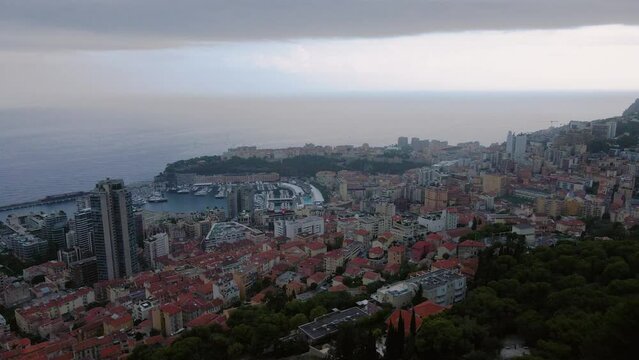 Aerial view over the city of Monaco, Monte Carlo. Footage was shoot from a drone at a higher altitude from above the city with the marina and sky scrapers on a stormy weather.