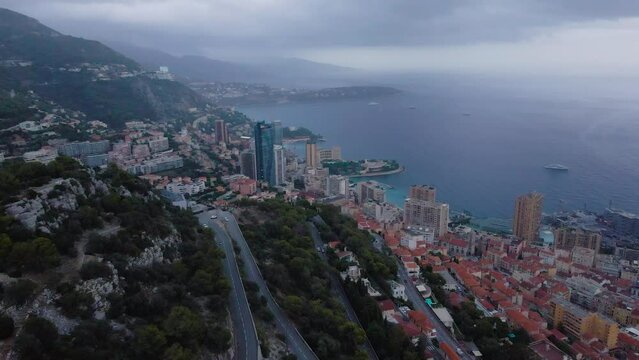 Aerial view over the city of Monaco, Monte Carlo. Footage was shoot from a drone at a higher altitude from above the city with skyscrapers and the coast in the view on a stormy weather.