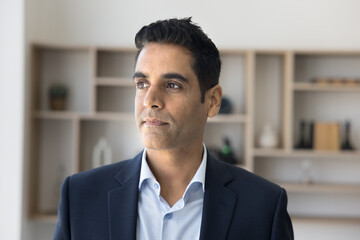 Serious pensive handsome CEO man in formal suit posing in office, looking away in deep thoughts,...