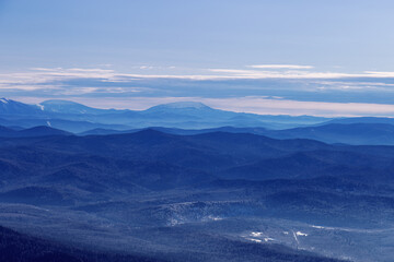 Winter nature panorama of far away blue mountains, picturesque view, aerial tonal perspective, monochrome photo of range mountains and blue sky, hills covered forest, great landscape in Altai