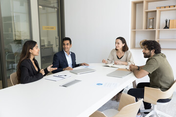 Business colleagues of different ages and races talking at meeting table in office negotiation room, brainstorming on creative ideas, discussing management process, teamwork strategy
