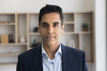 Serious handsome Indian executive man in formal cloth head shot portrait. Positive middle aged...