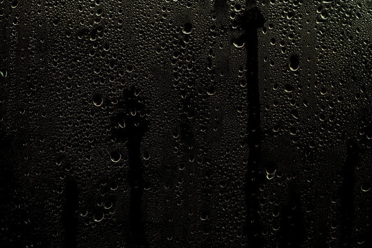 Wet window with water streaks. Glass with raindrops on a dark background. Background or overlay for use in design.