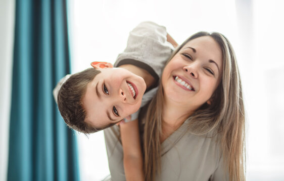 mother with her 4 years old little son playing in the bed.