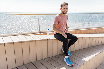 The coach is resting, sitting, training with sports clothes, running warm-up. A man smiling runner...