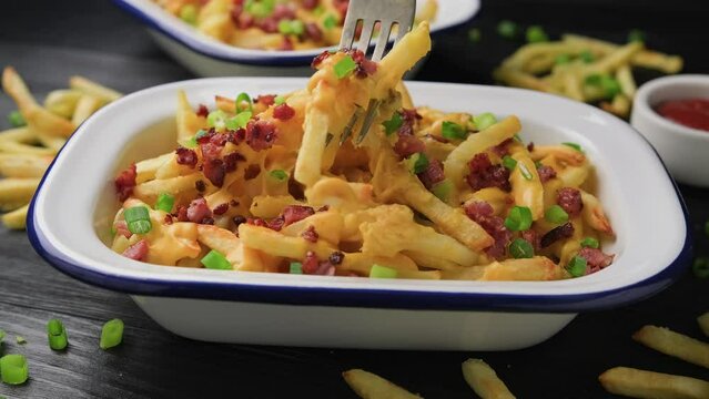 Eating Crispy French fries loaded with bacon, cheese sauce and spring onion