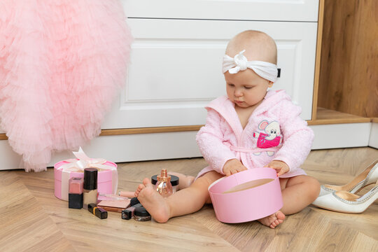 Cute little girl trying her mom s cosmetics. Pretty baby kid sitting on the floor among lots of beauty products. Small fashionista doing make up