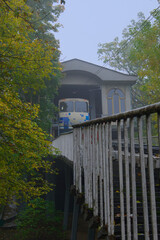 Mystery foggy autumn landscape view of funicular cabin in the upper station. Passengers are waiting for departure to the lower station. Funicular is popular transport among locals and tourists
