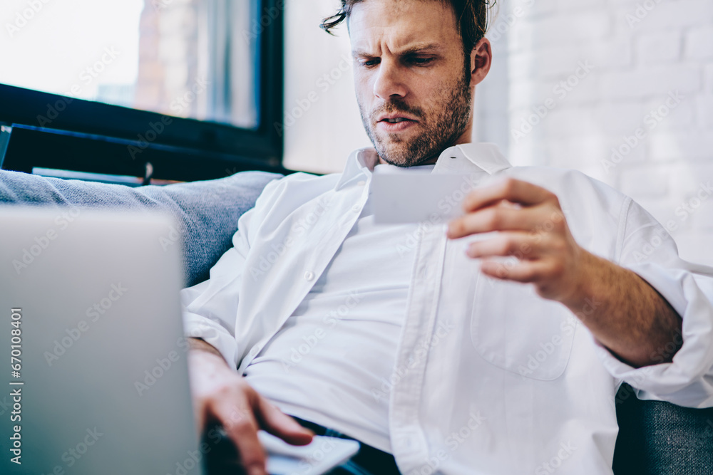 Poster hipster guy sending text message to colleague while sitting with modern laptop computer,