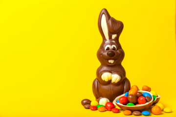 Easter chocolate bunny on a light texture table. Chocolate eggs and other sweets. Easter celebration concept. Easter sweets on the table. Place for text. copy space.