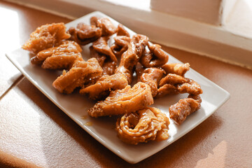 Moroccan chebakias on a white plate in a patio with plants