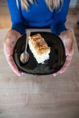 The woman holds food in her hand. the girl holds in her hands. Cake on plate.